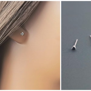 May include: A pair of silver stud earrings with small black heart charms.