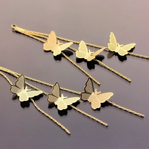 May include: A pair of gold earrings with multiple strands of chain and butterfly charms. Each earring has three butterfly charms.