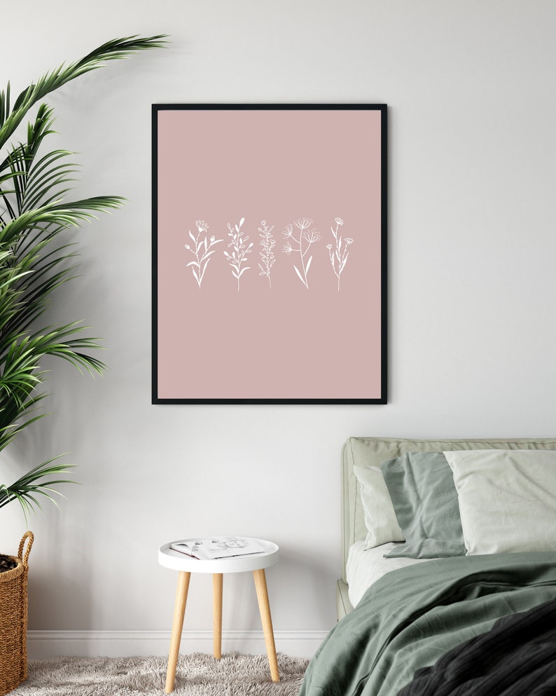 May include: A black framed print with a blush pink background and white line drawings of five different types of flowers.