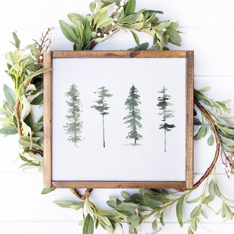 May include: A framed watercolor painting of four green trees on a white background. The trees are painted in a simple, minimalist style.