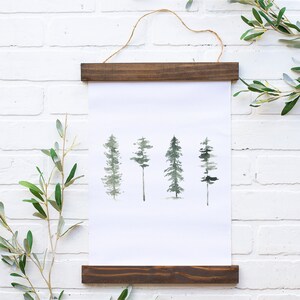 May include: A framed watercolor print of four stylized trees in shades of green on a white background. The frame is made of dark wood and has a hanging wire.