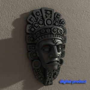 Peut inclure: Un masque de style aztèque gris foncé avec des détails complexes, notamment une coiffe et des traits du visage. Le masque est monté sur un mur texturé gris clair. Le texte "digital product" est visible.