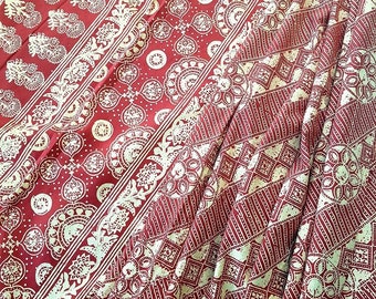 Può includere: Tessuto rosso con un motivo bianco. Il motivo presenta una varietà di forme geometriche e motivi floreali.