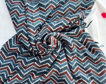May include: A blue and maroon cotton fabric with a chevron pattern. The fabric has a border with a floral design.