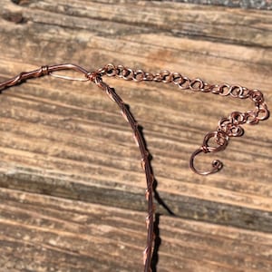 May include: A copper-coloured wire necklace featuring a twisted wire design and an adjustable chain extension with a hook clasp. The necklace is constructed from a single strand of wire wrapped in a spiral pattern, ending in a series of circular links.