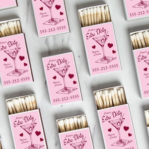 May include: Pink matchboxes with the text "Always Extra Dirty" and a martini glass illustration. Each box also features a phone number and the words "Martini Lounge" and "Call Me."
