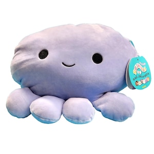 Peut inclure: Une peluche poulpe lavande avec des yeux noirs et une bouche souriante. Le jouet a huit tentacules souples et une étiquette attachée. L'étiquette porte les mots "Squishmallows" et "So Soft, Cuddle and Squeeze Me!"