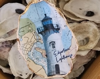 May include: A painted oyster shell with a map of Edgartown, Massachusetts and a lighthouse. The text "Edgartown Lighthouse" is written on the shell.