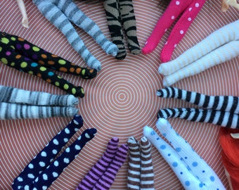 May include: A collection of colorful tights in various patterns, including polka dots, stripes, and geometric designs. The tights are arranged in a circle on a red and white background.