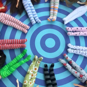 Pode incluir: Uma coleção de meias listradas e estampadas coloridas dispostas em círculo sobre um fundo listrado azul e branco.