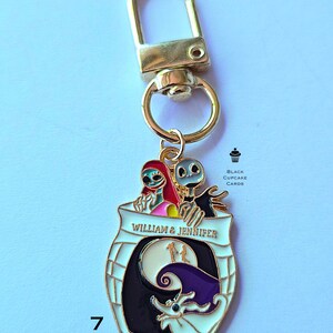 May include: A gold-colored keychain with a decorative charm featuring characters from "The Nightmare Before Christmas." The charm has a white border and includes the text "WILLIAM & JENNIFER." The design incorporates a moon, a bat, and other elements.