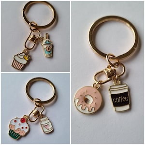May include: Two gold keychains with different charms. One keychain has a cupcake, a coffee cup, and a donut charm. The other keychain has a cupcake and a milk carton charm.