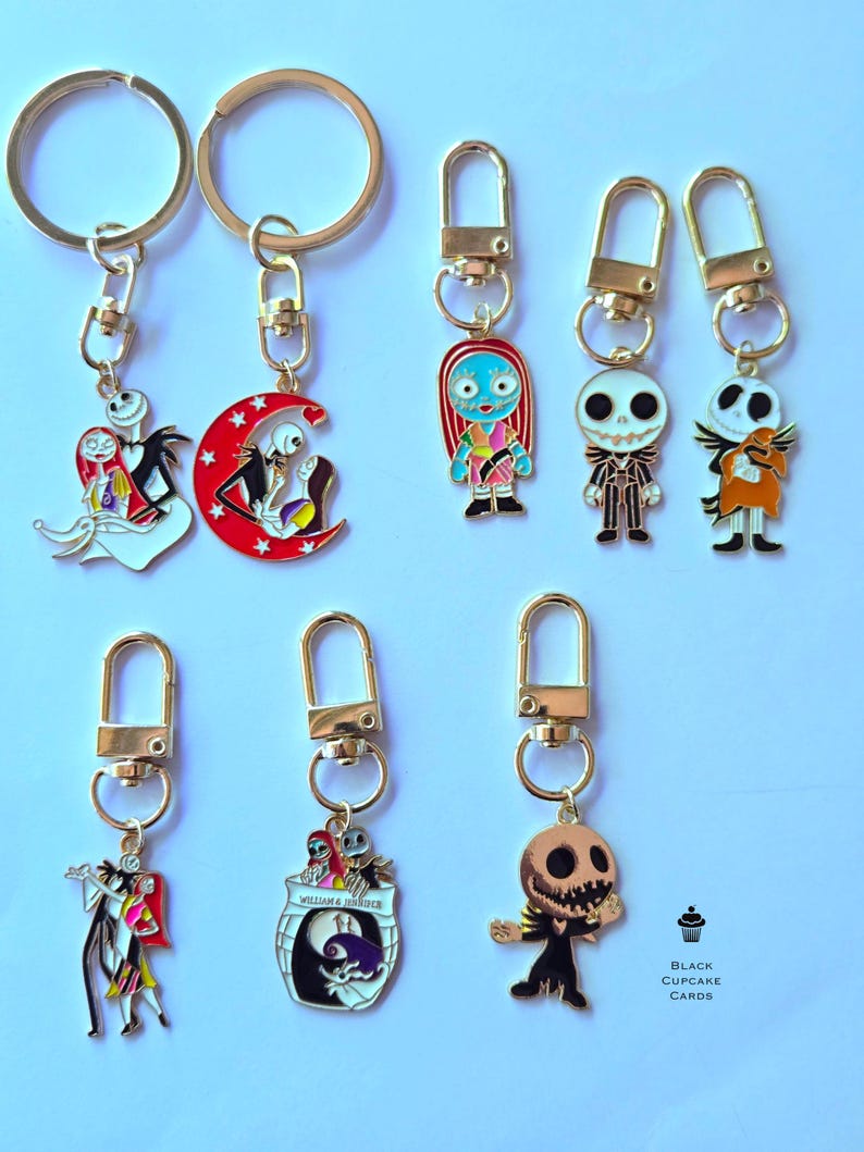 May include: Collection of gold-toned keychains featuring characters from "The Nightmare Before Christmas." Designs include Jack Skellington, Sally, and other characters. Each keychain has a lobster clasp for easy attachment. The keychains are colorful and detailed.