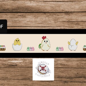 K&ouml;nnte beinhalten: Ein Kreuzstichmuster mit einem gelben K&uuml;ken, das aus einem Ei schl&uuml;pft, einem wei&szlig;en Huhn und einem Korb mit bunten Eiern. Das Muster ist gerahmt und enth&auml;lt den Text "Uscroidiga PuntoCroce".