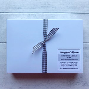 May include: A white gift box with a black and white checkered ribbon tied around it. The box has a label that reads "Shabbyheart Skincare Handmade Artisan Soap Men's Sampler Selection Contents - 50g Bars of Perfect Man, Creedence, Sherlock & Ginger, Amber & Bergamot www.ShabbyheartSkincare.etsy.com"