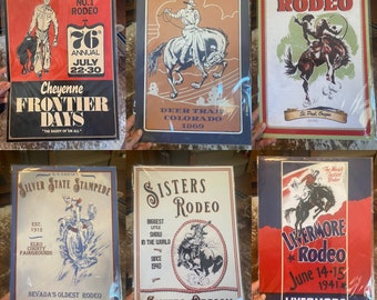 Puede incluir: Seis carteles metálicos vintage que anuncian diferentes rodeos. Los carteles muestran vaqueros montando a caballo, con texto que incluye el nombre del rodeo, la ubicación y las fechas. Los carteles son de varios colores, incluyendo rojo, azul, blanco y negro.