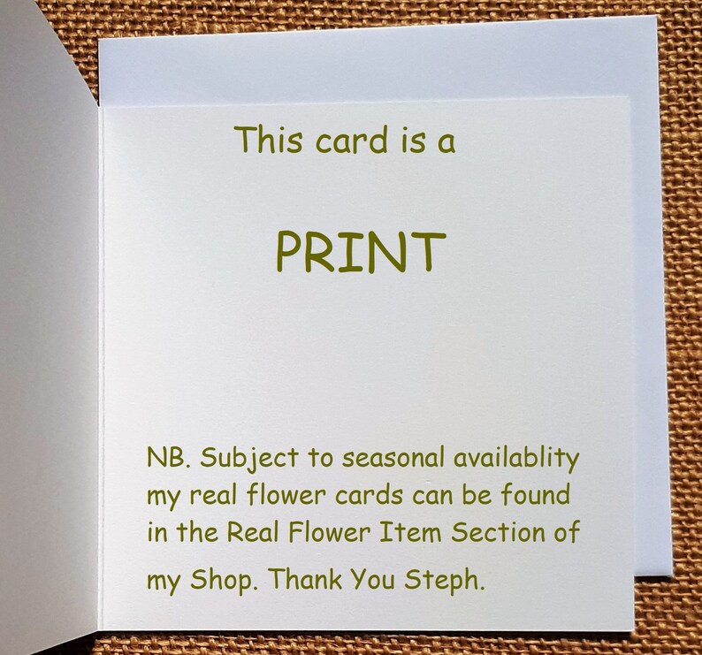 May include: A white greeting card with the text "This card is a PRINT" in green. The card also includes additional text in green, informing the reader about real flower cards. The card is open, revealing the inside.
