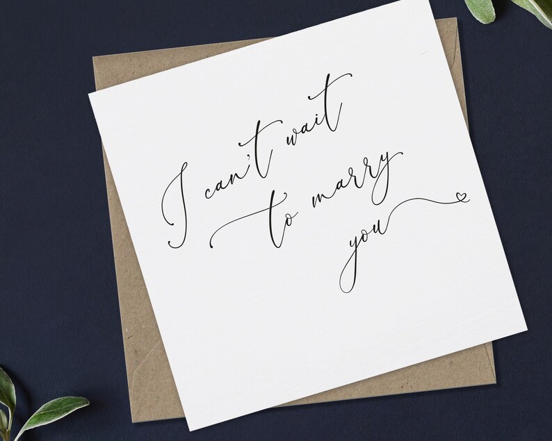 May include: A white card with black calligraphy that reads "I can't wait to marry you" with a small heart symbol at the end.