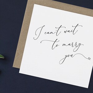 May include: A white card with black calligraphy that reads "I can't wait to marry you" with a small heart symbol at the end.