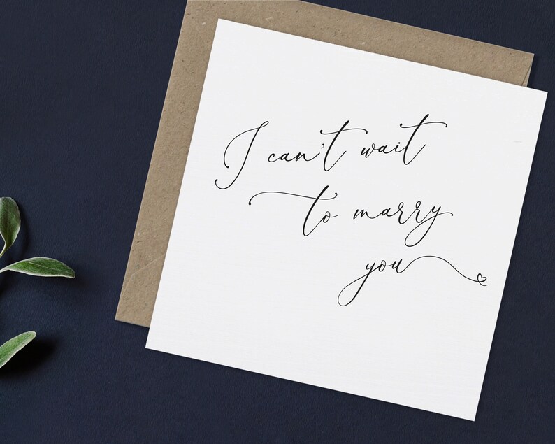May include: A white card with black calligraphy that reads "I can't wait to marry you" with a small heart symbol at the end.