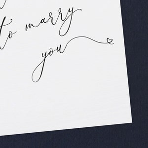 May include: A white card with black calligraphy that reads "I want to marry you" with a small heart at the end of the cursive writing.