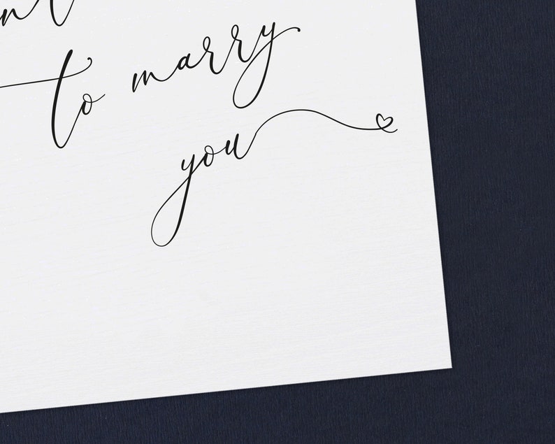 May include: A white card with black calligraphy that reads "I want to marry you" with a small heart at the end of the cursive writing.