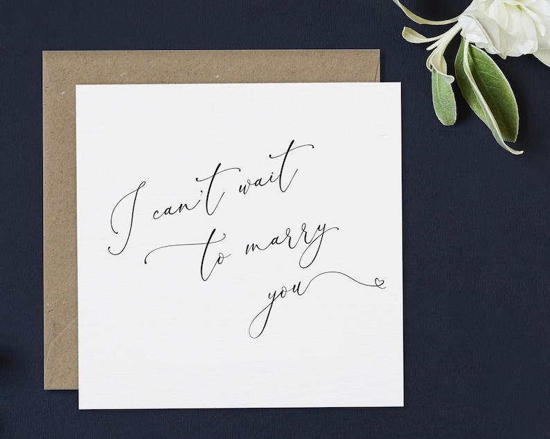May include: A white card with black calligraphy that reads "I can't wait to marry you" with a small heart symbol at the end.
