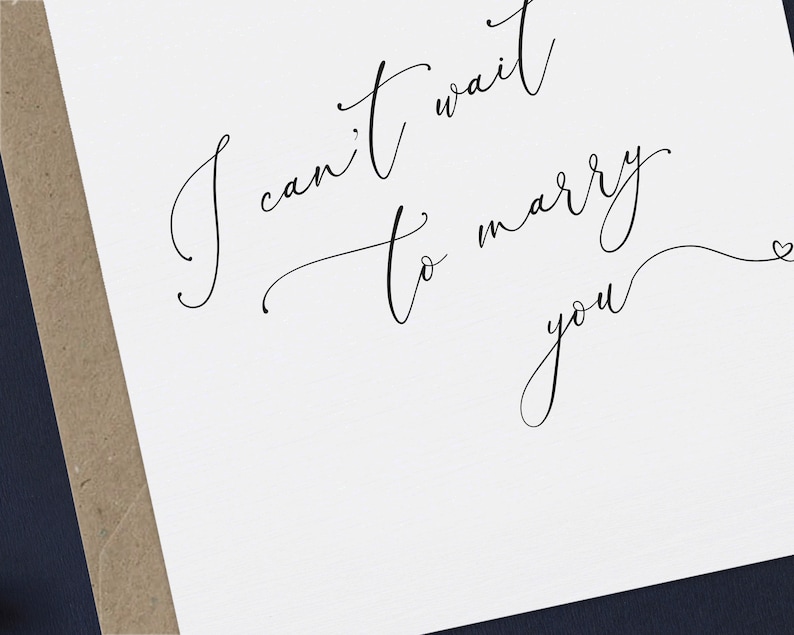 May include: A white card with black calligraphy that reads "I can't wait to marry you" with a small heart symbol at the end.