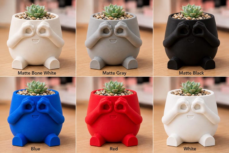 May include: A collection of whimsical, small succulent planters in matte finishes: bone white, gray, black, blue, red, and white. Each planter has a round body with arms and legs, and a face with hands over the eyes. The planters are filled with soil and a small succulent.