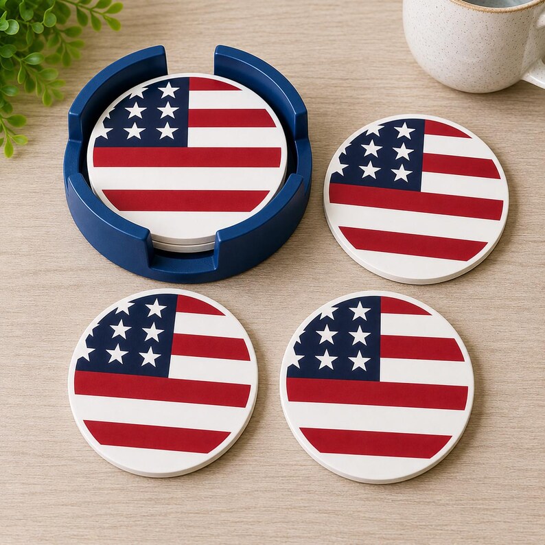 May include: Set of four round coasters with a patriotic American flag design. The coasters feature a white background with red stripes and a blue square with white stars. They are displayed with a blue holder.