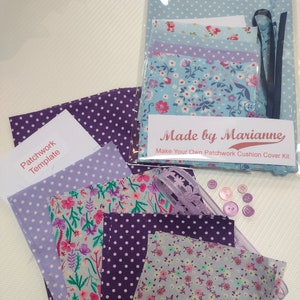 May include: A patchwork cushion cover kit with purple and blue floral fabric, polka dot fabric, and a template. The kit includes buttons, ribbon, and lace. The packaging says "Made by Marianne Make Your Own Patchwork Cushion Cover Kit".