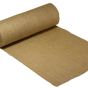 May include: A roll of natural brown burlap fabric. The fabric is woven with a textured pattern and is rolled up with the end of the fabric extending out.