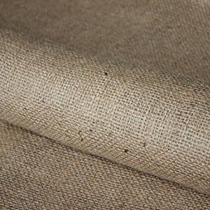 May include: Close-up of a natural brown burlap fabric with a rough texture. The fabric is folded over, showing the woven pattern.