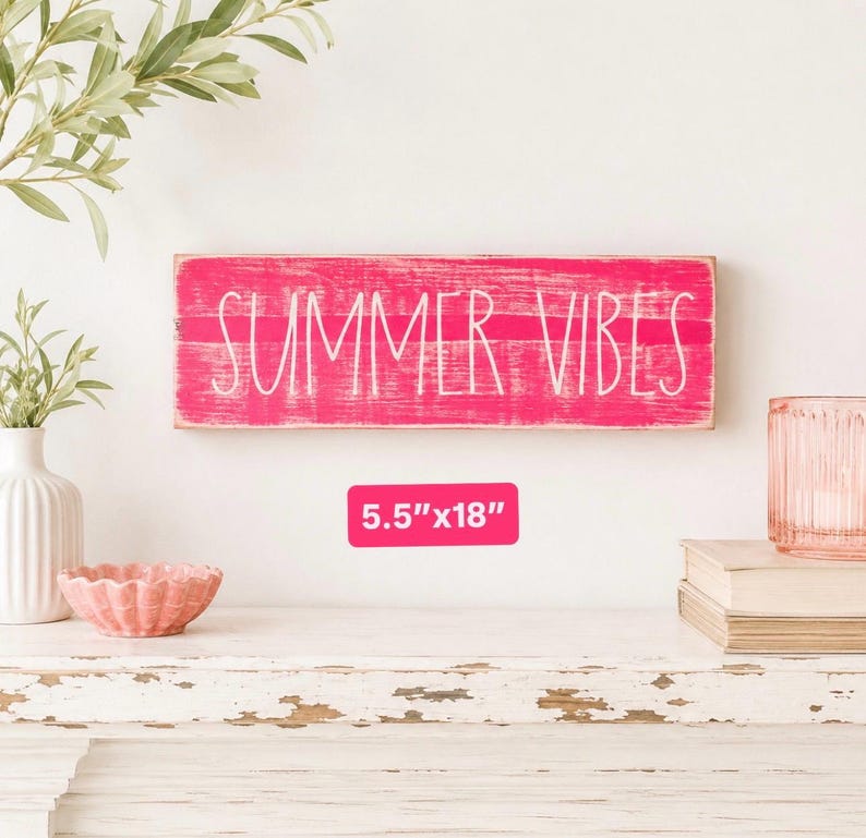 May include: A rectangular wooden sign with a distressed hot pink finish and the white text "SUMMER VIBES" printed across the centre. A pink label below the sign displays the dimensions 14 cm by 46 cm in white text.