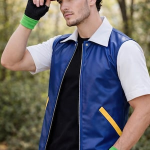 May include: A red and white baseball cap with a green logo, a blue vest with a white collar and yellow accents, a black t-shirt, light blue jeans, and black fingerless gloves with green wristbands. The vest features a full-length silver zipper.