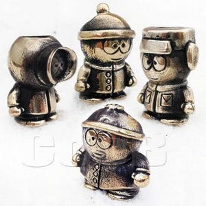 May include: Four small bronze figurines of cartoon characters wearing winter clothing. The characters are all wearing hats and coats. The figurines are approximately 5 cm tall.