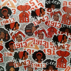 May include: A collection of stickers featuring a variety of designs, including a woman with an afro, an elephant, and the text "1913". The stickers are in red, white, and black.