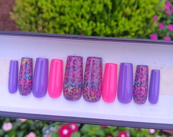 Könnte beinhalten: Ein Set mit zehn falschen Nägeln in einer Box. Die Nägel sind in verschiedenen Farben, darunter Lila, Pink und ein Leopardenmuster.
