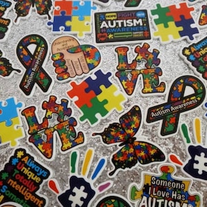 May include: Assortment of colorful autism awareness stickers featuring puzzle pieces, butterflies, ribbons, and handprints. The stickers have text that reads "Autism Awareness", "Hope Fight Autism Awareness", "Always Unique Totally Intelligent Sometimes Mysterious", "Understanding and Acceptance", "Love", and "Someone I Love Has Autism".