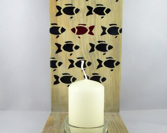 May include: Wooden candle holder with a single candle in a glass holder. The holder is decorated with a pattern of black fish, with one red fish in the center.