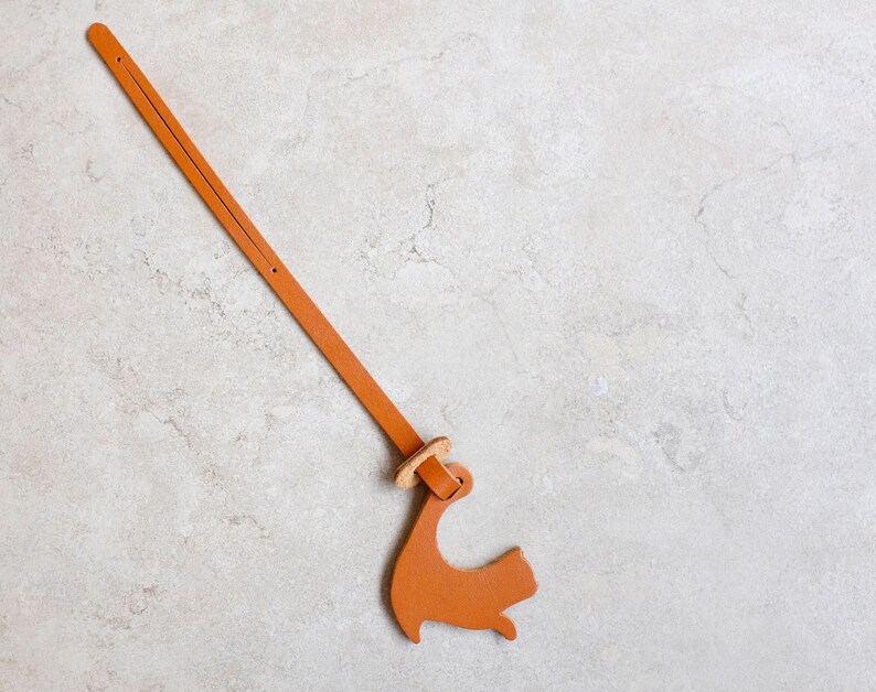 Peut inclure: Une lani&egrave;re en cuir marron avec un petit charme en cuir marron en forme de chien attach&eacute; &agrave; l'extr&eacute;mit&eacute;.