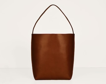 May include: A brown leather tote bag with a single top handle.