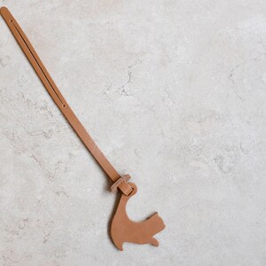 Peut inclure: Un marque-page en cuir marron avec une silhouette de chat &agrave; l'extr&eacute;mit&eacute;.