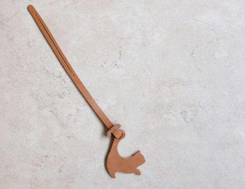 Peut inclure: Un marque-page en cuir marron avec une silhouette de chat &agrave; l'extr&eacute;mit&eacute;.
