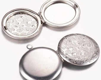 May include: Silver-colored oval locket with a floral design on the front and inside. One locket is open, revealing a blank interior, while the other is closed. The lockets have a small loop at the top for attaching to a chain.