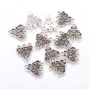 May include: Silver triangle pendant connectors with a decorative swirl design. Each connector has three loops for attaching jewellery components.
