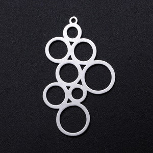 Könnte beinhalten: Silberner Anhänger mit einem Design aus überlappenden Kreisen, die ein geometrisches Muster bilden.