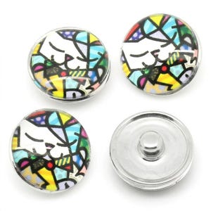 May include: Four circular snap buttons featuring a colorful stained-glass style pattern of a cat face. Three buttons display the cat graphic with black outlines and vibrant yellow, blue, and red segments, while one button shows the plain silver metal back.