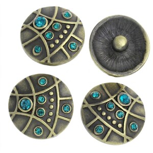 May include: Three circular metal buttons with an antique brass finish, featuring a raised grid pattern, small embossed dots, and embedded teal crystals. One button is shown from the reverse side, displaying a central circular metal snap fastener.