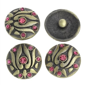 May include: A set of four round metal snap buttons with an antique brass finish. Three buttons feature a raised leaf-like pattern accented with small, round, bright pink crystals. One button shows the plain, concave underside with a central stud.